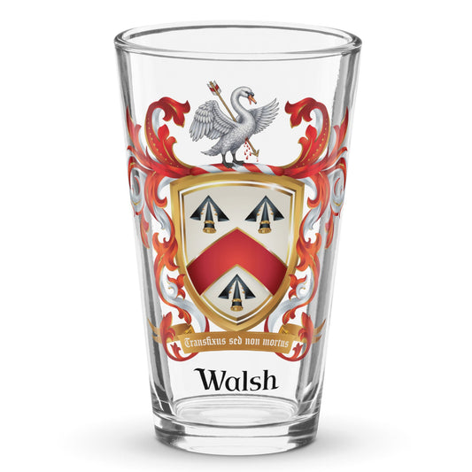 A clear classic pint beer glass on a white background, printed with the Walsh Family Crest featuring a white swan on a shield with 3 arrowheads and a chevron.