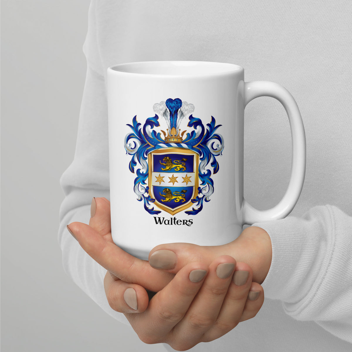 A person in a white long-sleeve top holds a white ceramic mug with a blue and gold Walter family crest printed on the front, with the name 'Walters' below it.