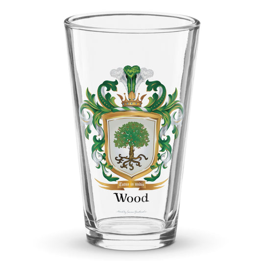 A clear classic pint beer glass on a white background, printed with the Wood Family Crest featuring a white shield and an oak tree.