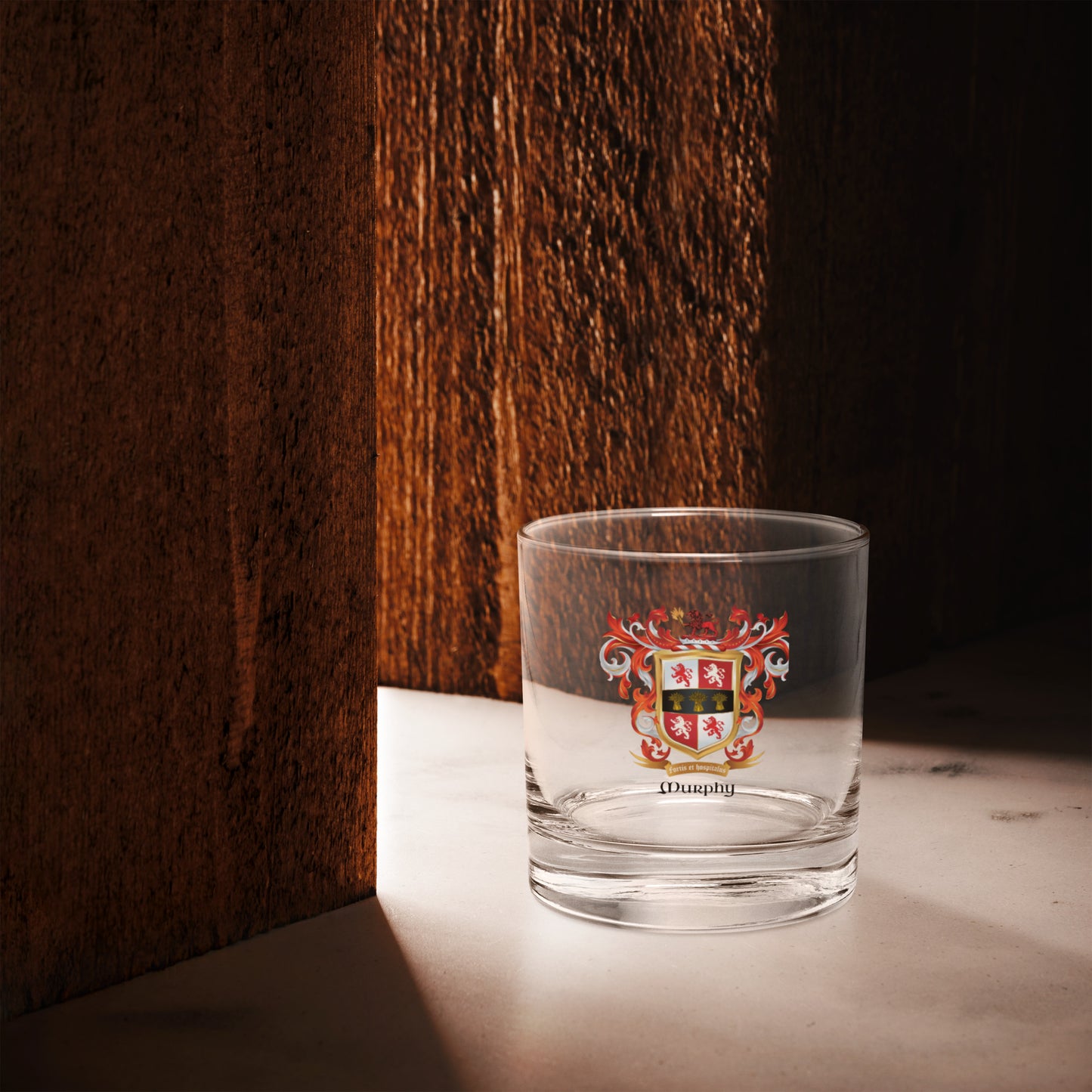Clear glass with a A Murphy Family Crest on white background on a wooden surface