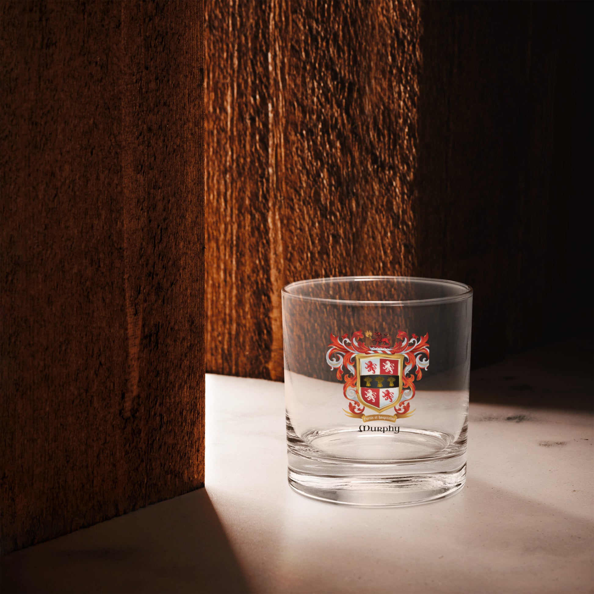 Clear glass with a A Murphy Family Crest on white background on a wooden surface